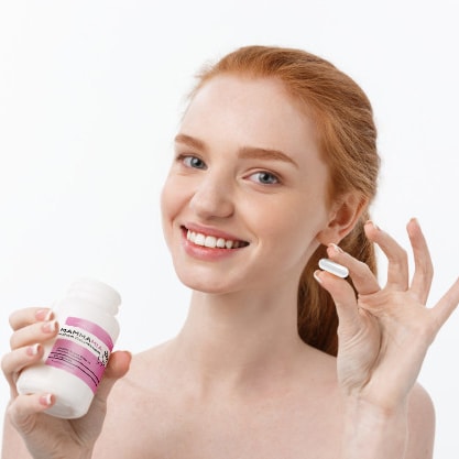 Regular use of breast pills is important to achieve satisfactory results. The girl is smiling and holding a pill in her hand.